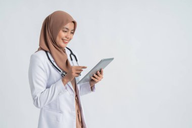 Müslüman Asyalı kadın doktor tablet bilgisayar kullanıyor.