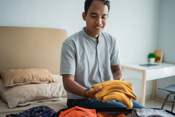 Ásia homem colocando seu roupa no o mala — Fotografia de Stock