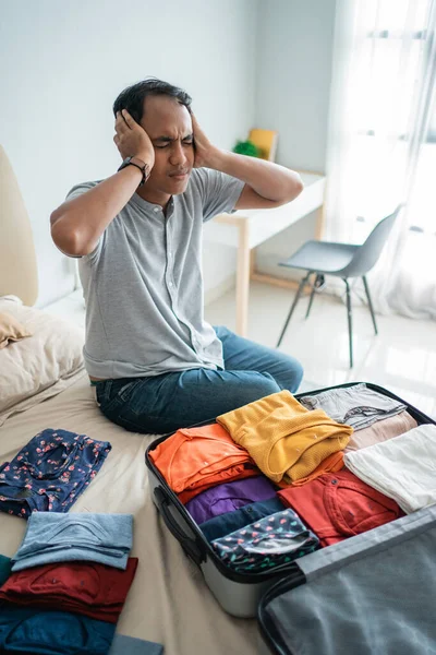 Jovem estressado depois de receber um cancelamento de bilhete de voo ao preparar suas roupas — Fotografia de Stock