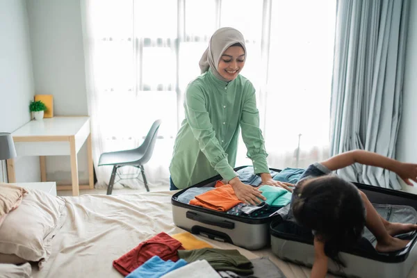 Mãe asiática prepara roupa para ser levada acompanhada por sua filha está brincando — Fotografia de Stock
