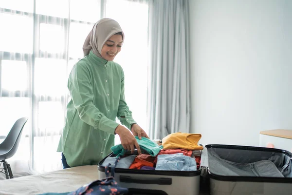 Mulheres muçulmanas bonitas preparando roupas para serem colocadas em uma mala — Fotografia de Stock