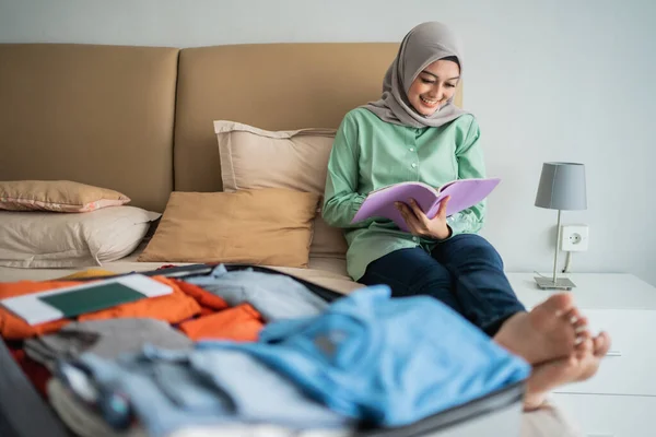 Hijab mujer sentada en la cama mientras mira la lista de artículos —  Fotos de Stock