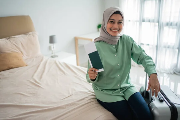 Ασιάτισσα μουσουλμάνα χαμογελάει κρατώντας ένα εισιτήριο και μια βαλίτσα — Φωτογραφία Αρχείου