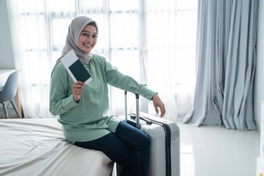 Gülümserken elinde bilet tutan peçeli kadın.