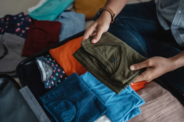 A fiatalember a bőröndbe pakolja a ruháit. — Stock Fotó