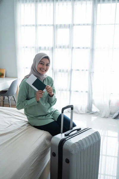 Asiatische muslimische Frau lächelt mit einem Ticket und einem Koffer — Stockfoto