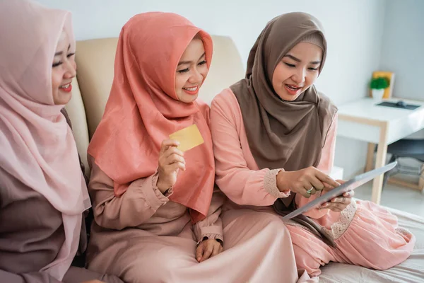 Mujeres musulmanas asiáticas usando tableta para buscar artículos en la tienda en línea cuando se quedan en casa —  Fotos de Stock