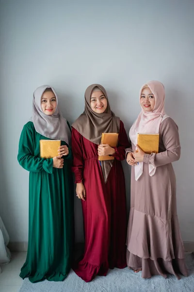 Drei lächelnde muslimische Frauen halten das heilige Buch des Al-Koran in der Hand — Stockfoto