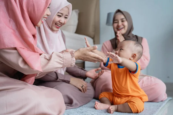 Tiga wanita muslim menikmati bermain dengan anak kecil ketika duduk di lantai — Stok Foto
