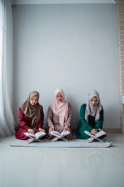 Три девушки в хиджабах вместе читают священную книгу Аль-Корана — стоковое фото