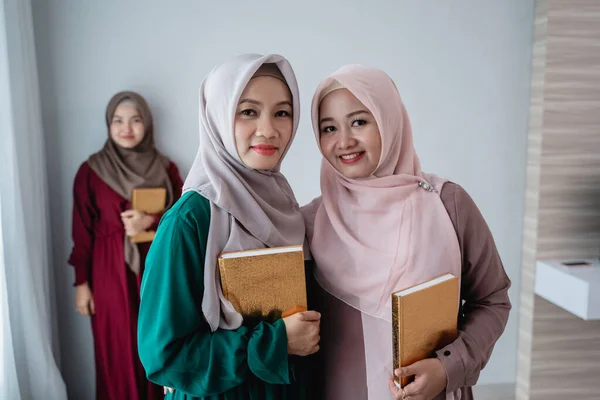 Dvě hidžábské ženy s úsměvem drží svatou knihu Al-quran — Stock fotografie