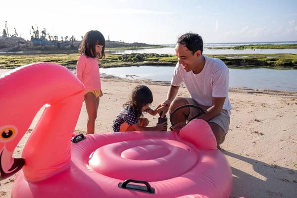 Père aidé sa fille à pomper une bouée de flamant rose — Photo
