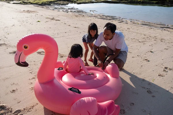 Père et deux filles pompage une bouée de flamant rose avant utilisé pour jouer — Photo