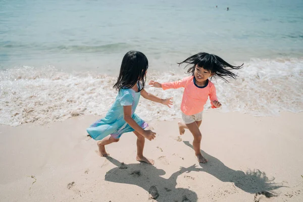파도를 피하기 위해 뛰어가는 아시아 소녀 두 명 — 스톡 사진
