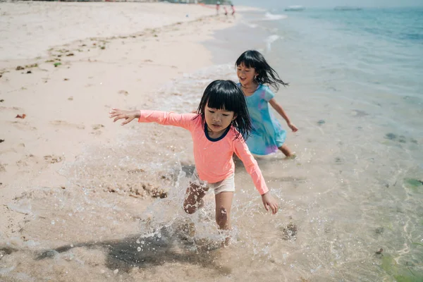Дві маленькі азійські дівчини бавляться на пляжі. — стокове фото