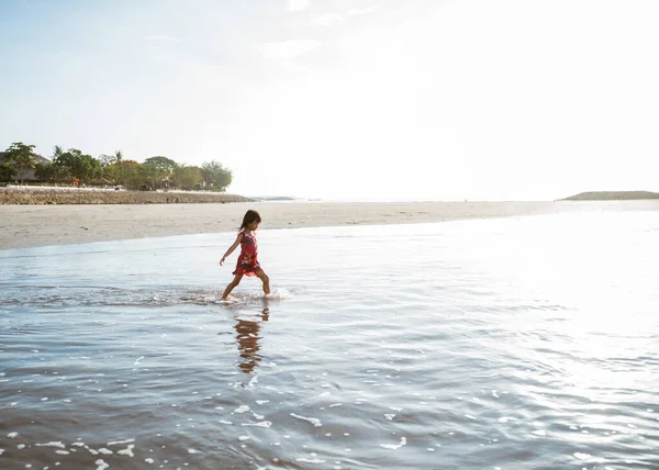 Little girl running on the beach while playing water — Stock Photo, Image