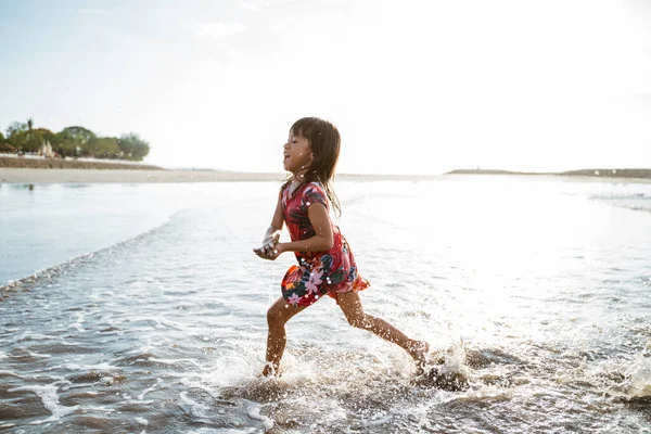 Κοριτσάκι που τρέχει στην παραλία ενώ παίζει νερό — Φωτογραφία Αρχείου