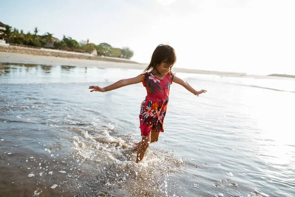 Klein meisje loopt op het strand terwijl ze water speelt — Stockfoto