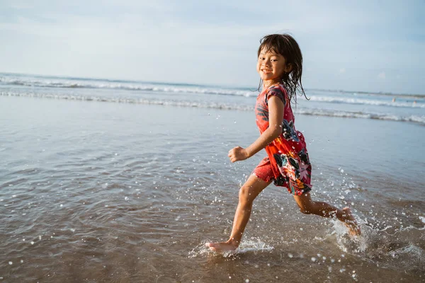 Маленька дівчинка біжить на пляжі, граючи у воду — стокове фото
