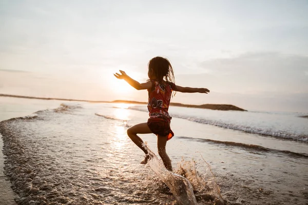 Asiatisches kleines Mädchen läuft und springt am Strand — Stockfoto