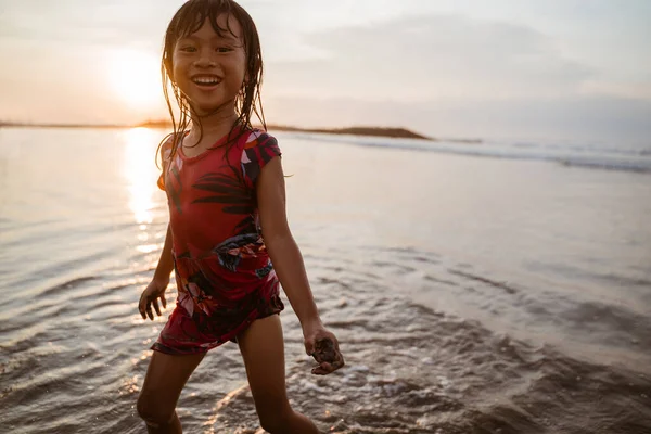Kislány fut a parton, miközben játszik a víz — Stock Fotó
