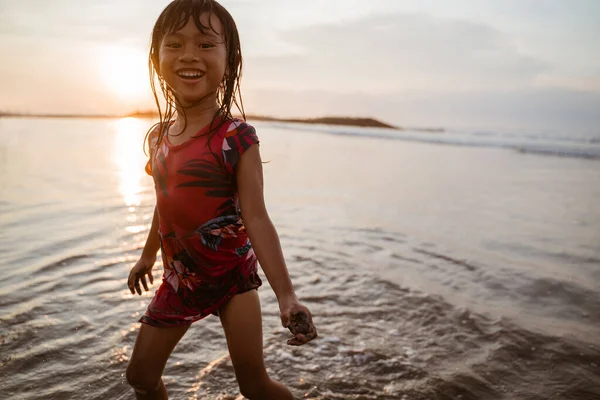 Petite fille courant sur la plage tout en jouant de l'eau — Photo