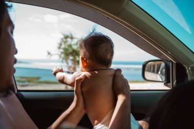 Baba pencereden dışarı bakmak için bebeğini taşıyor.
