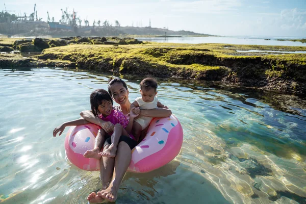 Mère et ses deux enfants rient en montant sur l'anneau de bouée — Photo