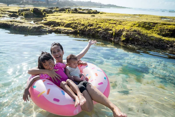 Asiatique mère et son deux enfants rire tandis que équitation sur l 'bouée anneau — Photo