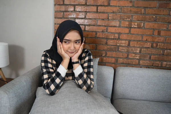 Скучная мусульманка, сидящая на диване — стоковое фото