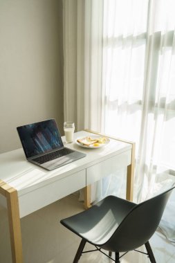 Laptop bilgisayarı kahvaltı yemeğiyle birlikte masada.