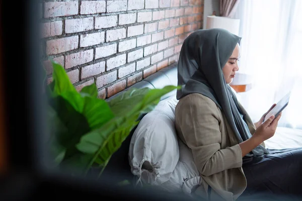 ベッドの上に座ってタブレットを使用してイスラム教徒のアジア人女性 — ストック写真