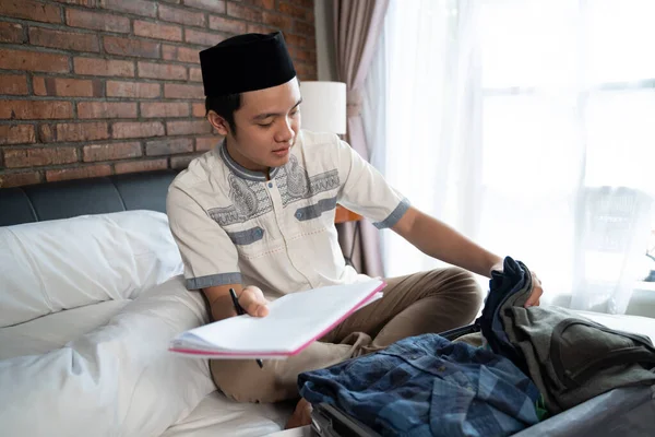 Muslim young male holding a paper checklist for luggage — Stock Photo, Image