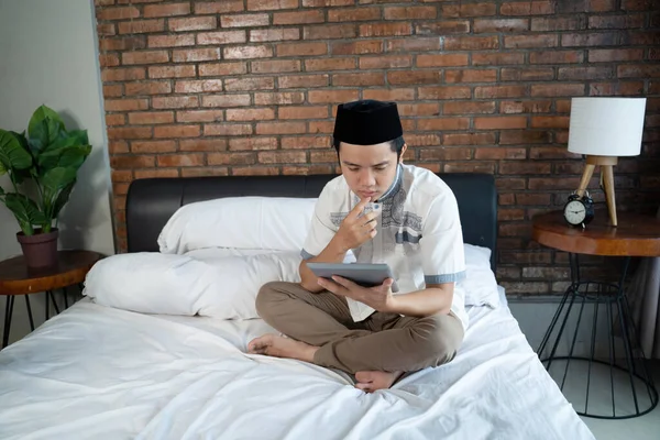 Muzułmanie azjatyccy używają tabletek siedzących na łóżku — Zdjęcie stockowe