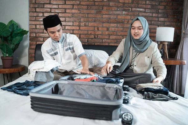Азиатская мусульманская пара готовит одежду и чемодан перед возвращением домой — стоковое фото