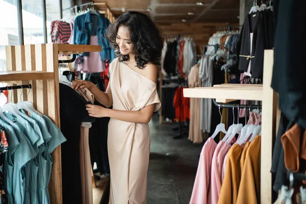 Mulher olhando para algumas roupas na loja boutique de moda — Fotografia de Stock
