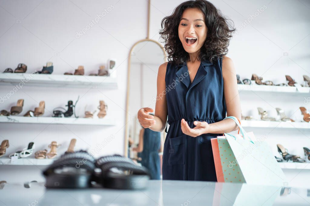 excited asian woman shopping looking at shoes