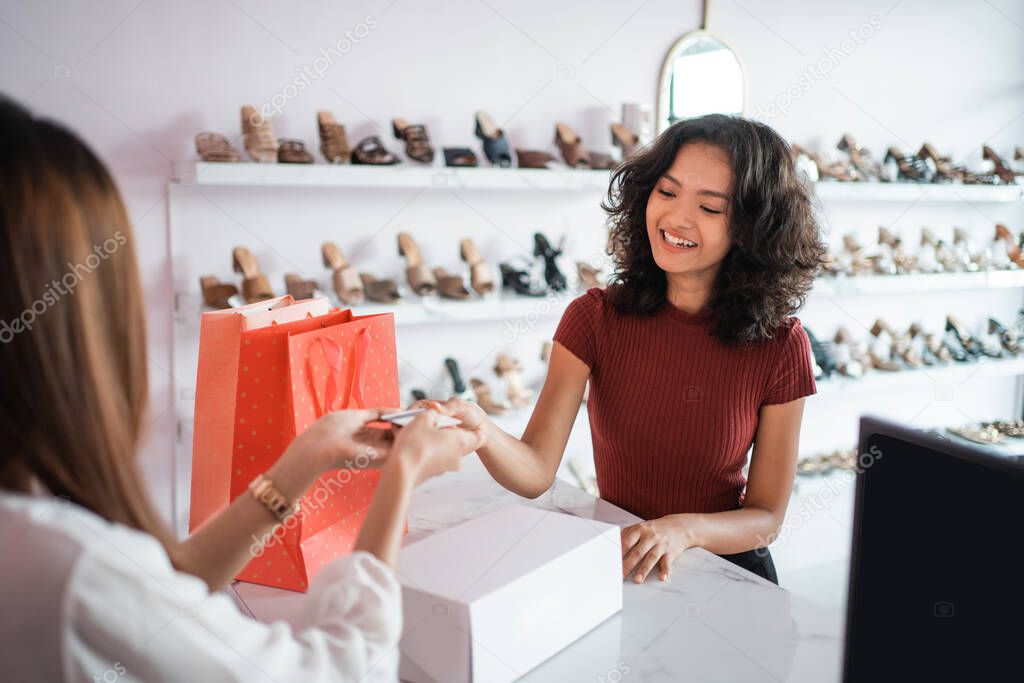 asian woman shop assistant with shoe boxes at store
