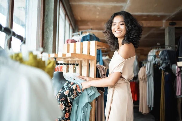 Жінка дивиться на якийсь одяг в модному магазині — стокове фото