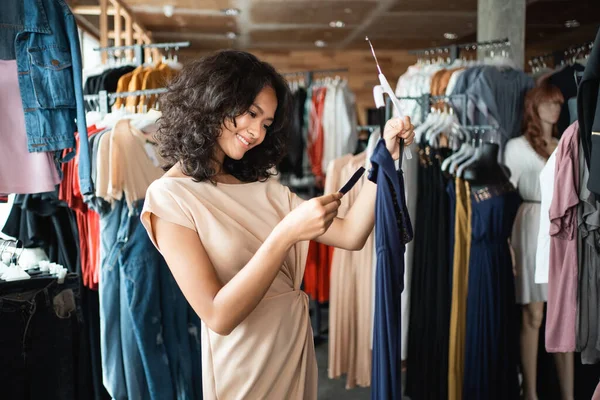 Mujer mirando una etiqueta de precio mientras que el vestido de compras — Foto de Stock