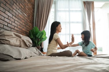 Kardeş yatakta birlikte oynuyor.