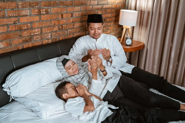 Мусульманская семья молится на кровати — стоковое фото
