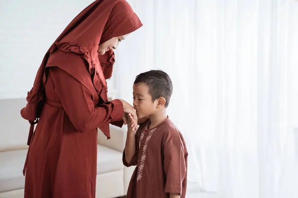 Asyalı çocuk bayramını kutlarken annesinin elini öpüyor.- — Stok fotoğraf