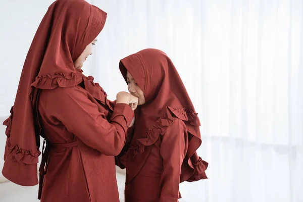 Азиатская мусульманская девушка целует его матери руку, когда празднует счастливый праздник Ул - — стоковое фото