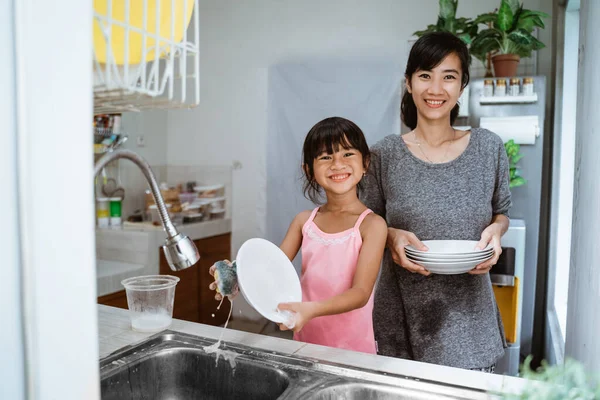 Pequeña niña ayudar a su madre en lavar platos — Foto de Stock