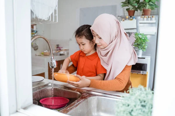 Bambina aiuto suo madre in lavaggio piatti — Foto Stock