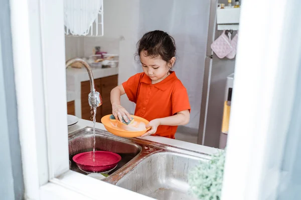 asian little girl wash the dishes
