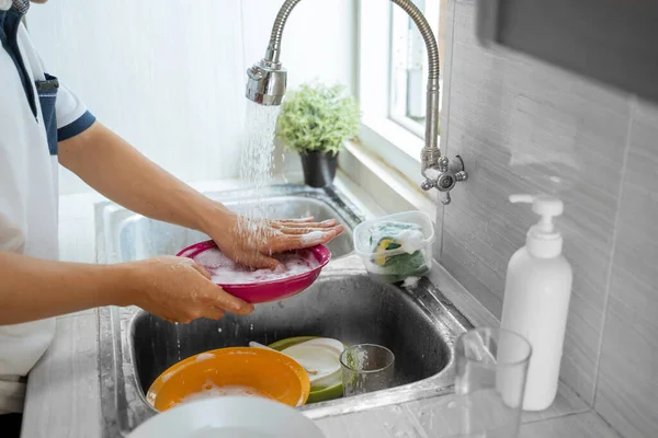 Lava los platos con una esponja en el fregadero —  Fotos de Stock