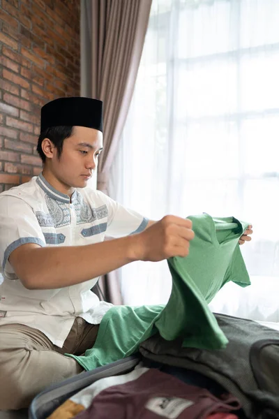 Jovem muçulmano preparando e embalando roupas — Fotografia de Stock