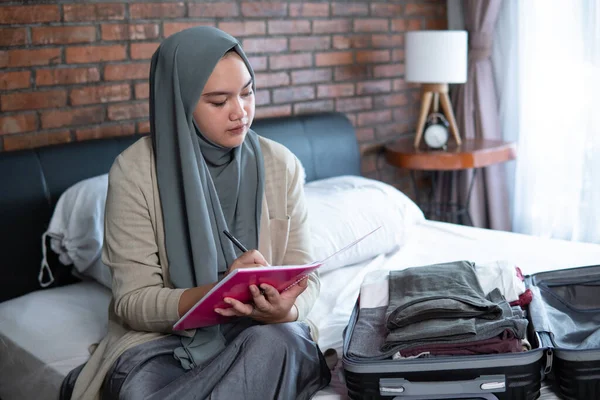 Musulmán asiático mujer chequeo lista de equipaje — Foto de Stock
